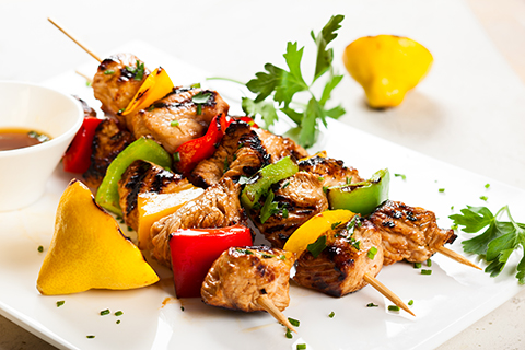 3 soy-glazed grilled chicken kabobs on skewers with red, green and yellow peppers